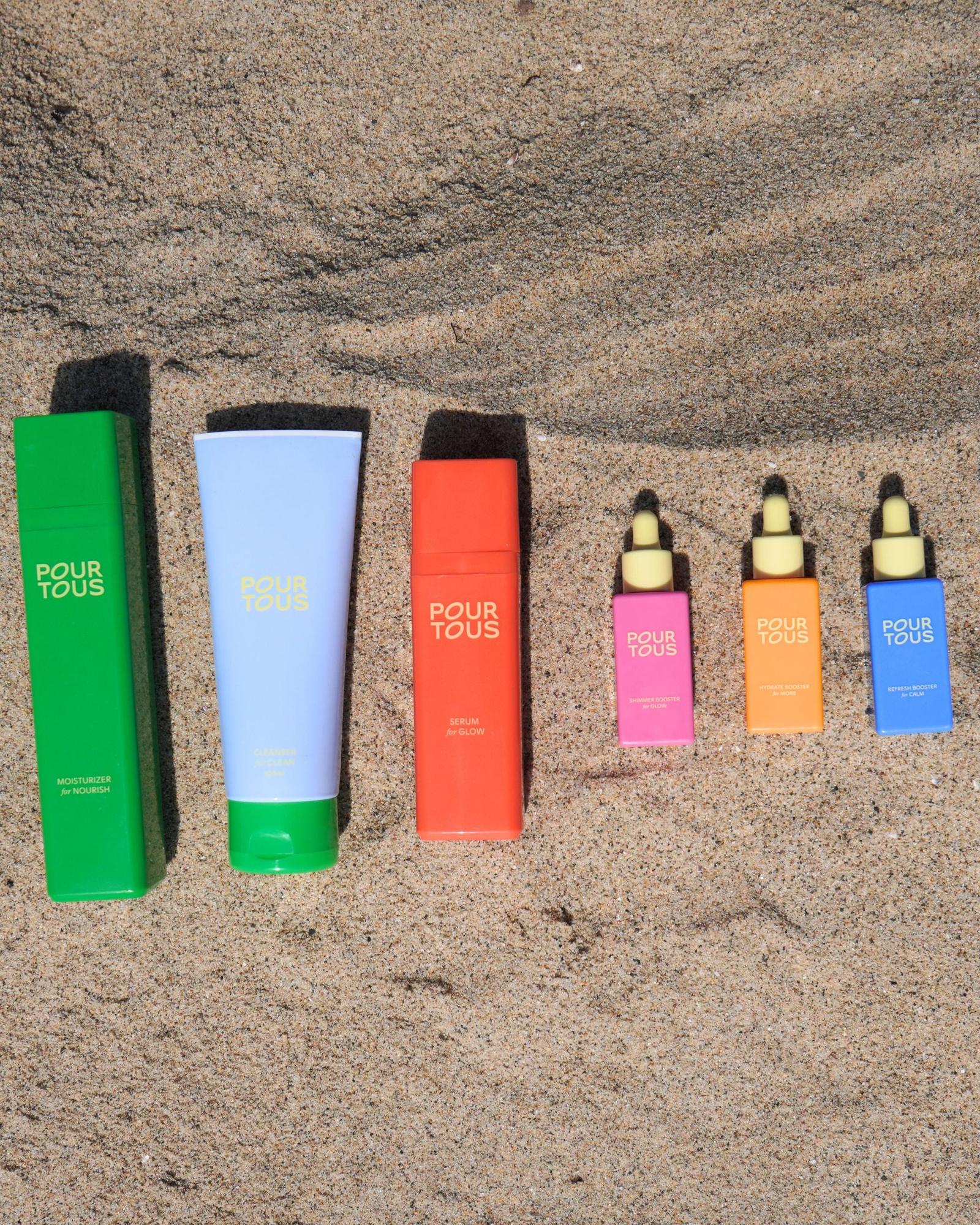Pour Tous skincare products on sand