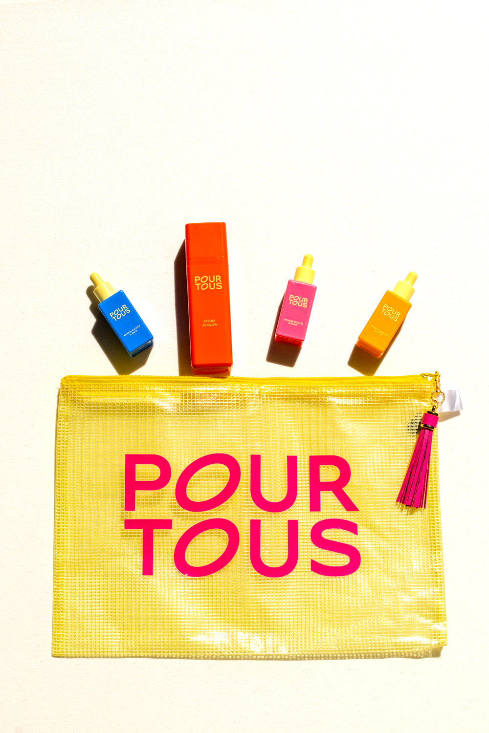 Colorful Pour Tous skincare products with yellow pouch.