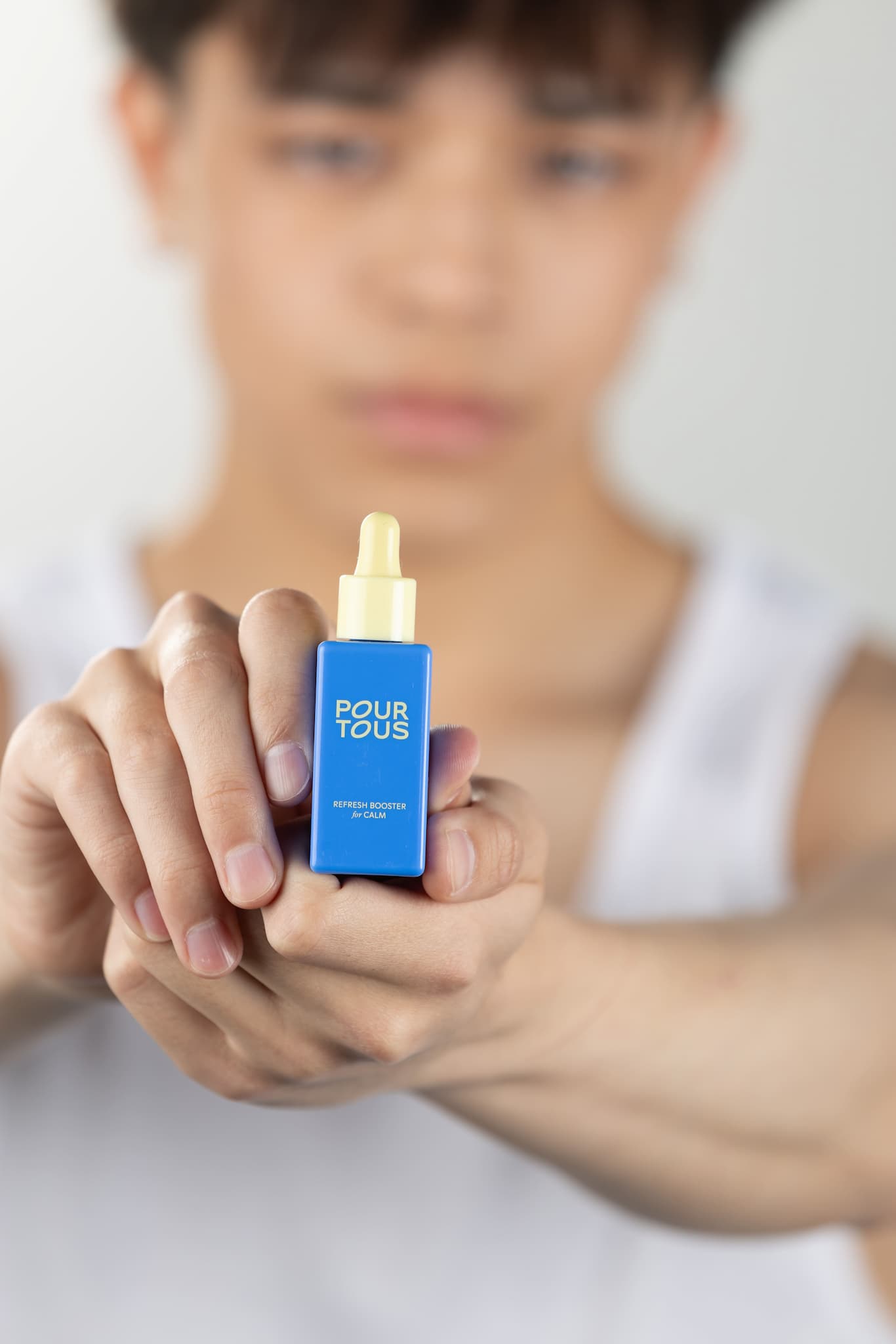 "person holding Pour Tous skincare bottle"