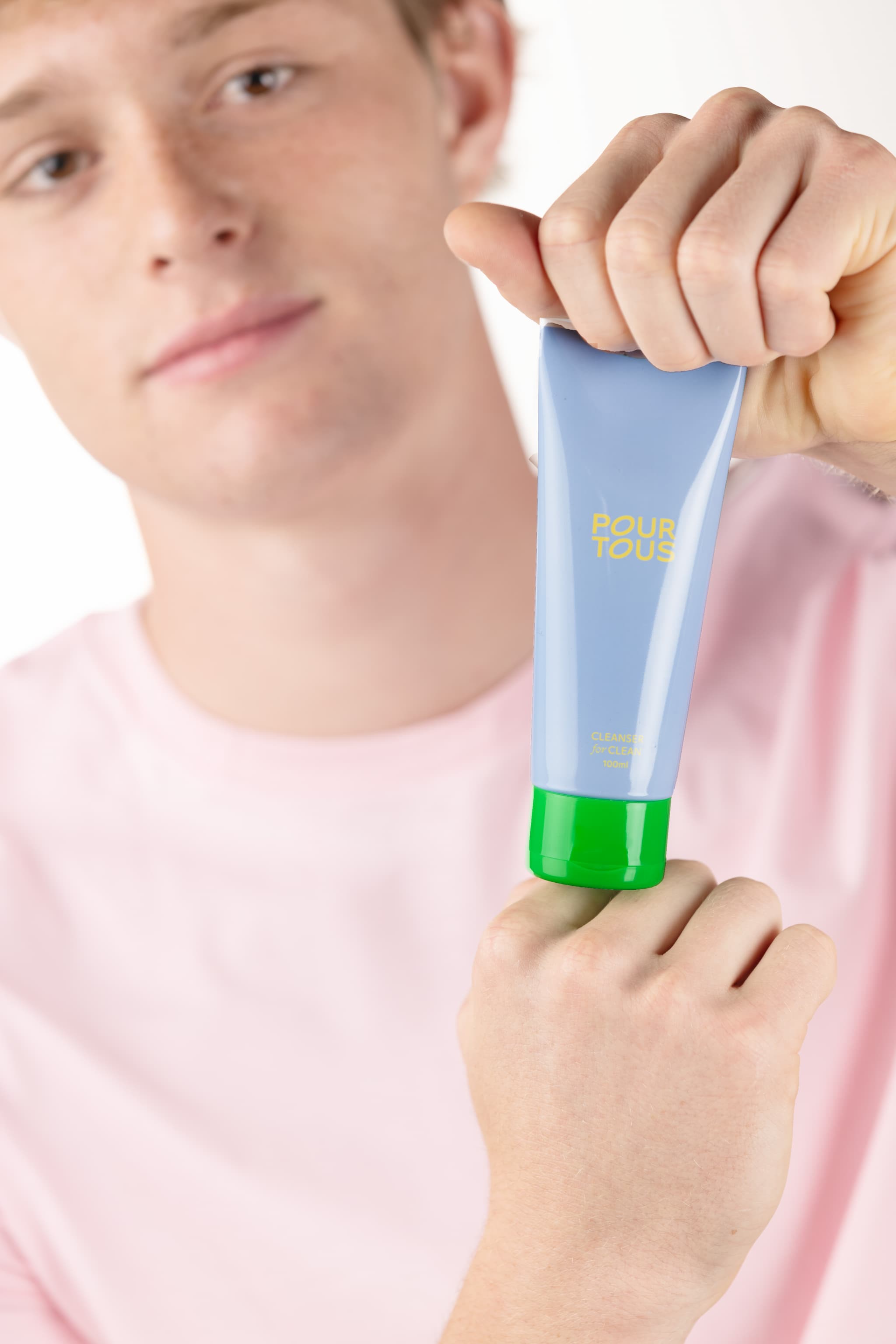 Man holding blue skincare cleanser tube.