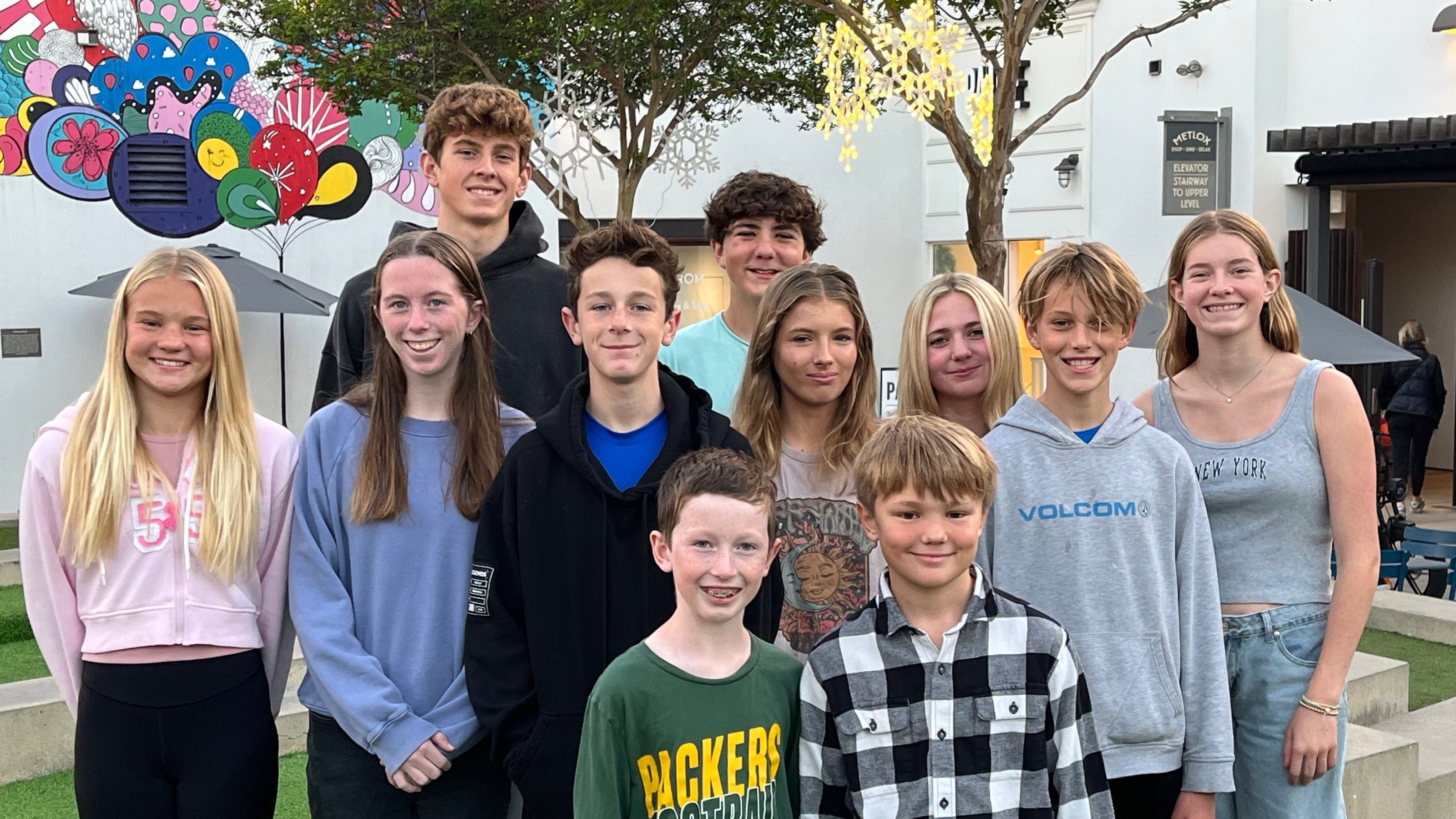 group of teenagers posing outdoors near school building