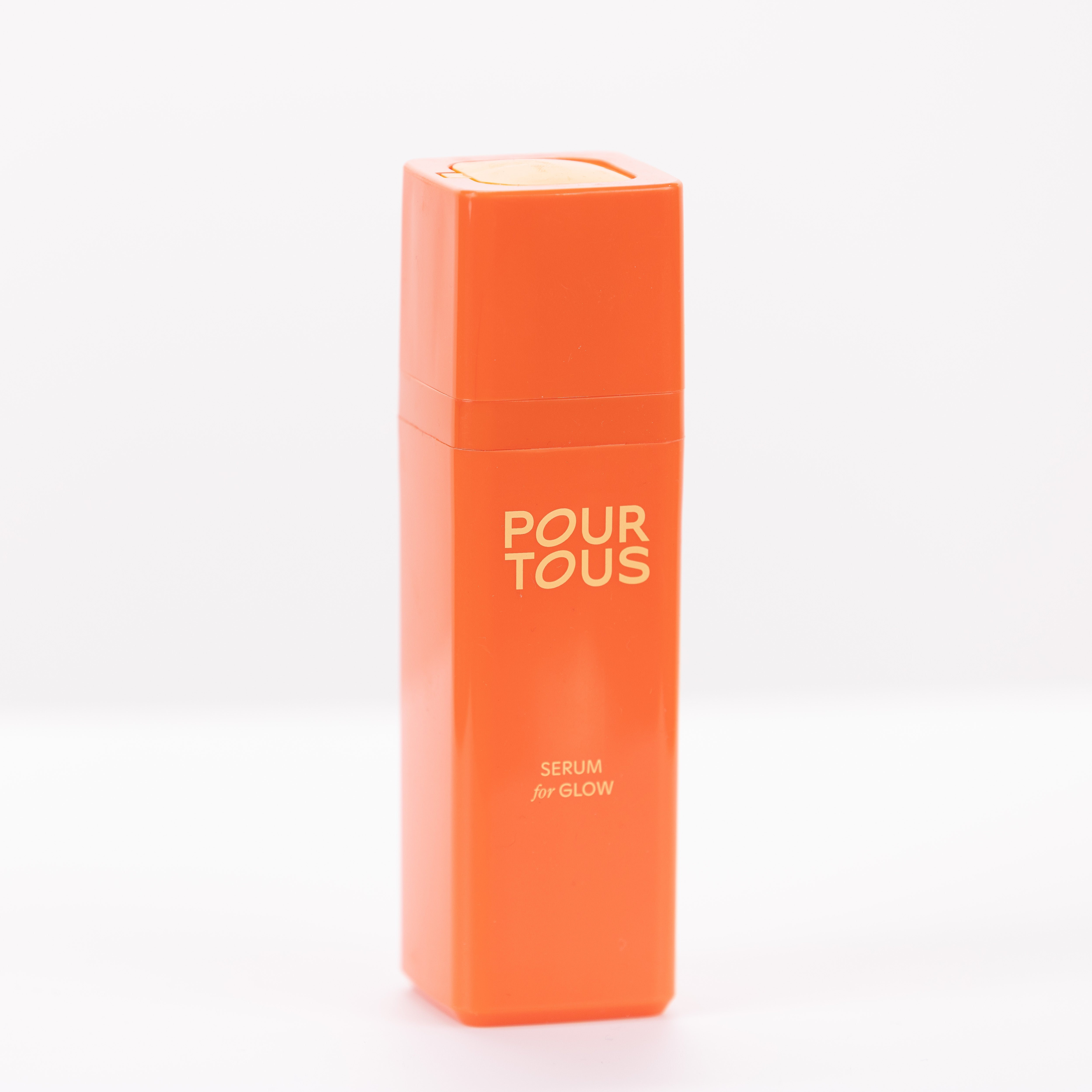 Orange serum bottle labeled "Pour Tous" for glow.