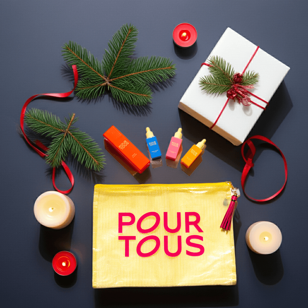 Gift set with skincare products, candles, pine branches, red ribbon, and yellow pouch on dark background.